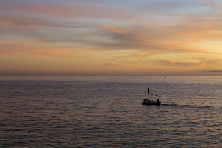 Un bateau de pêche partant vers le large au soleil couchant depuis le port de Cassis