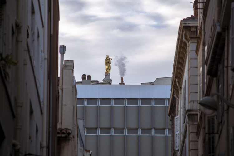 Depuis la rue du Petit Chantier dans le 7ème arrondissement de Marseille, par-dessus les toits dépasse juste la statue en or qui orne Notre-Dame de la Garde.