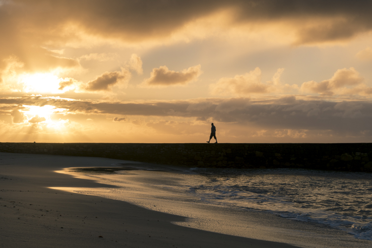 Un homme marche au coucher du soleil sur une jetée à Costa Teguise sur l'île de Lanzarote dans l'archipel des Canaries