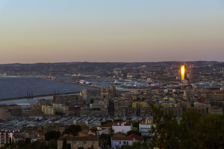 La tour CMA-CGM sur le port autonome de Marseille est frappé par un rayon de soleil qui se reflète dans sa façade vitrée.