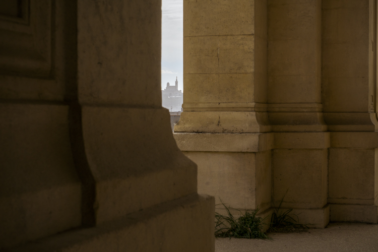 Une vue sur la Basilique Notre-Dame-de-la-Garde entre deux colonnes du Palais Longchamp à Marseille.