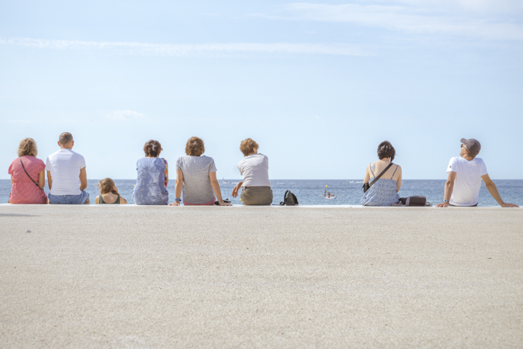 Un groupe de personnes assises face à la mer sur la plage de la Grande Mer à Cassis.