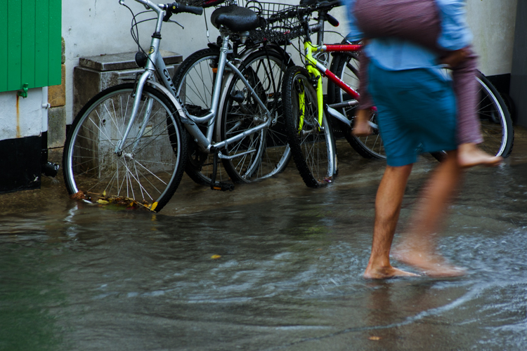 Un homme pieds nus porte sur son une jeune fille pour éviter qu'elle ne se mouille les pieds dans cette rue rempli de 10 centimètres d'eau.
