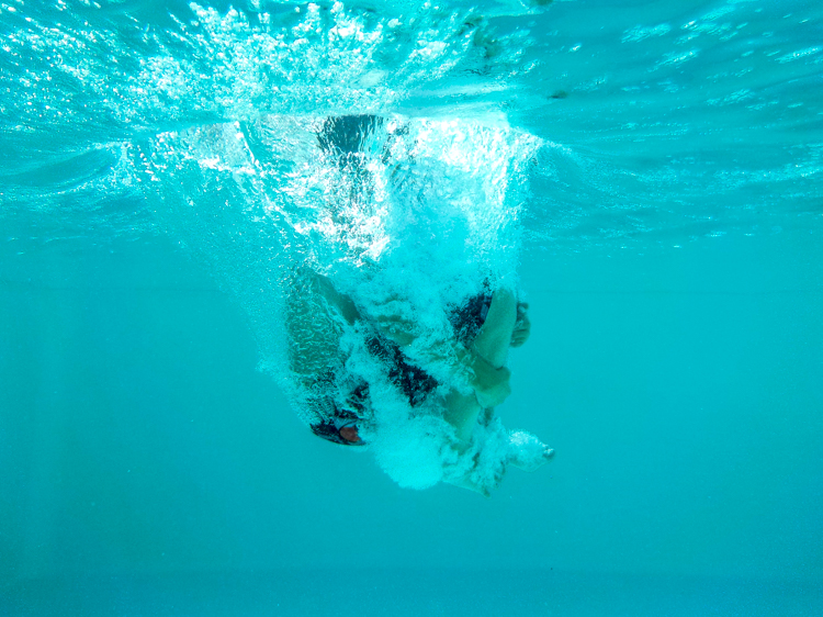 Un plongeon dans la piscine photographié sous l'eau.